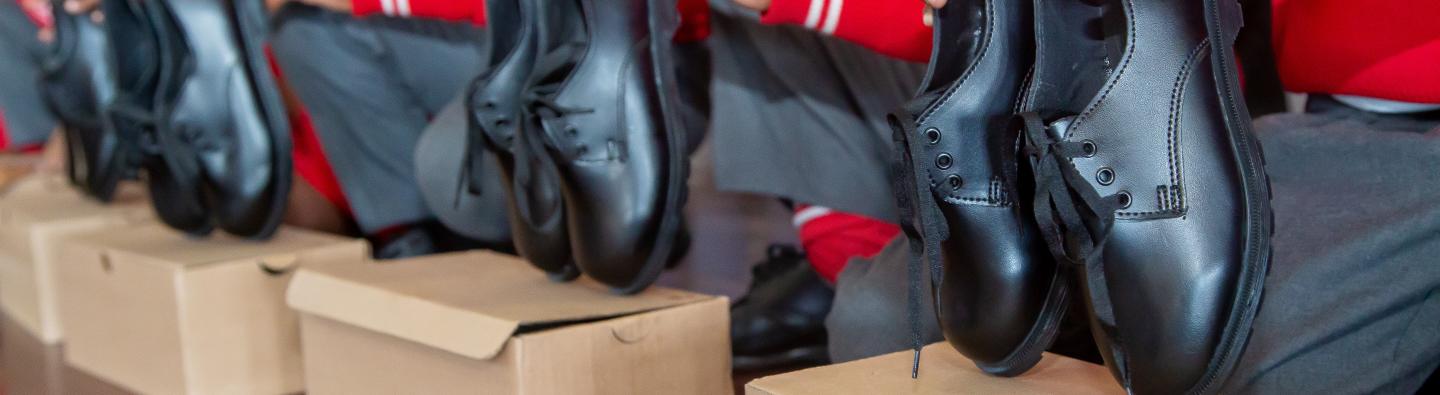 School learners holding donated school shoes made from recycled gumboots